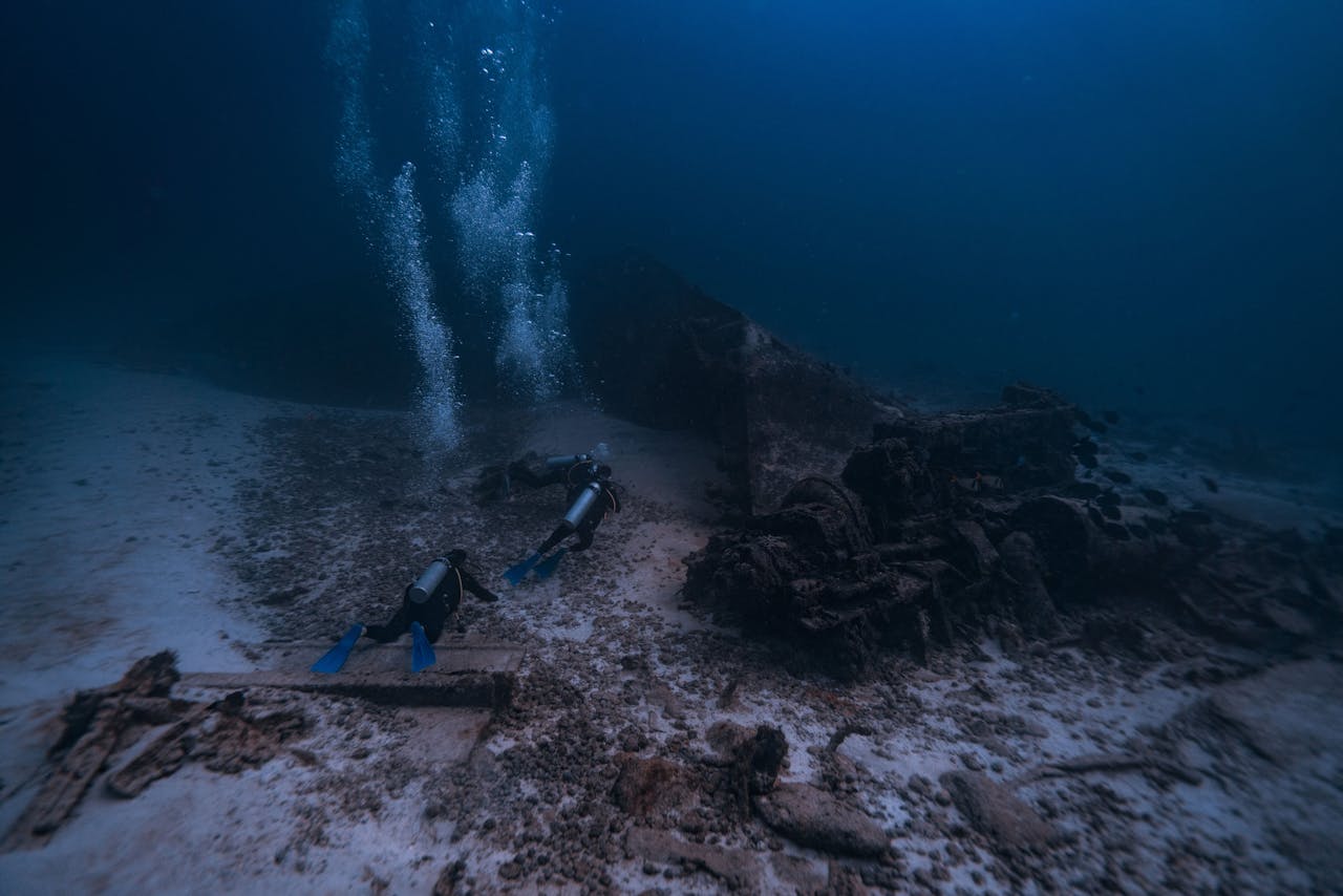 Two scuba divers explore an underwater shipwreck off the coast of Isla Mujeres, Mexico.